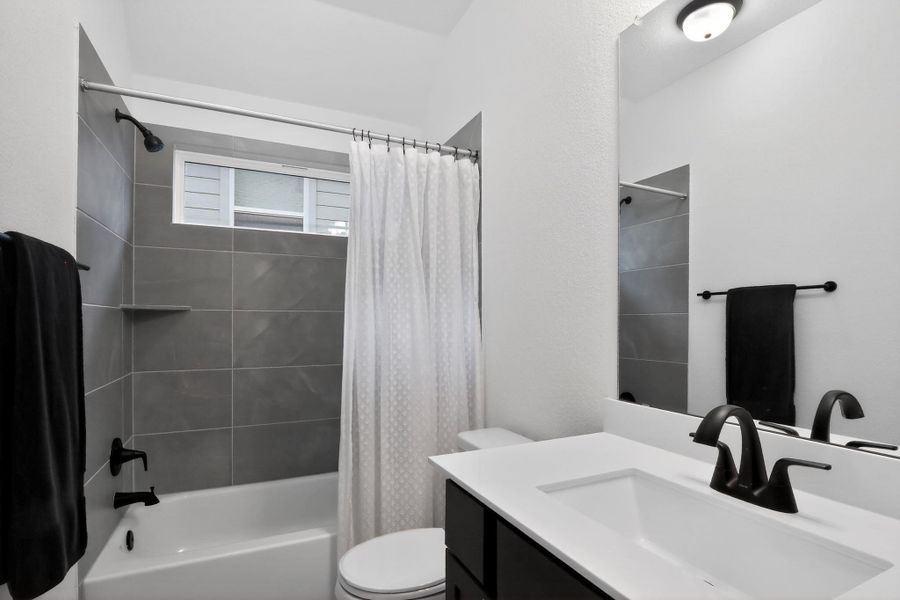 Bathroom featuring a white tub and shower with gray subway tile surround and built-in shower shelf Bathroom featuring a white tub and shower with gray subway tile surround and built-in shower shelf