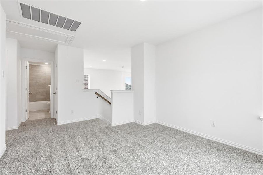 Unfurnished room featuring attic access and light carpet