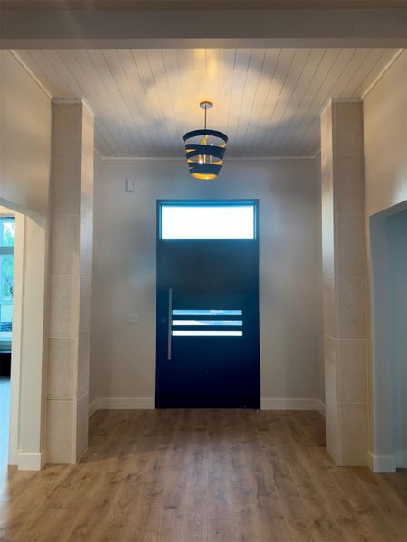 Warm wood flooring and detailed panel ceiling highlights complement this entry architectural transition. Warm wood flooring and detailed panel ceiling highlights complement this entry architectural transition.