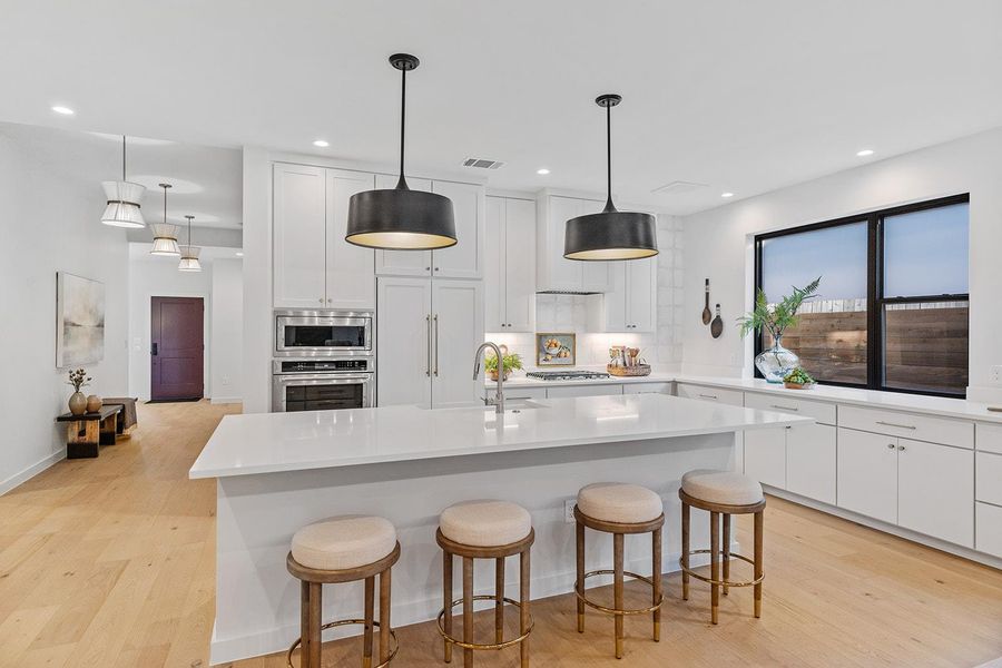 Kitchen with white cabinets, light wood-type flooring, a breakfast bar area, pendant lighting, and recessed lighting