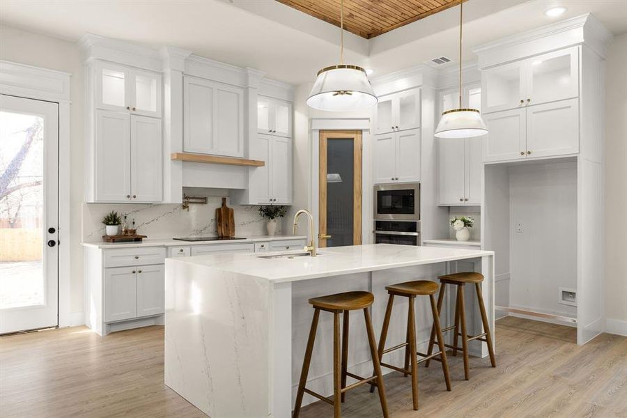 Kitchen featuring a tray ceiling, visible vents, decorative backsplash, a sink, and built in microwave