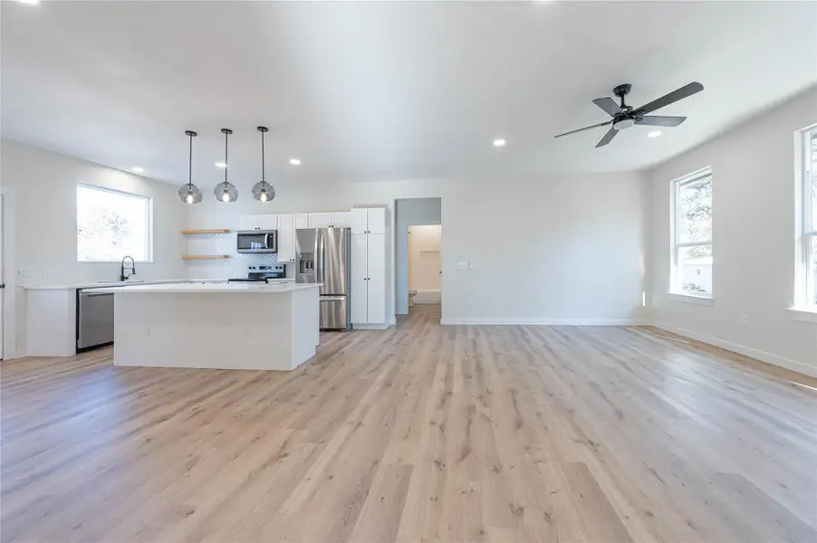 Kitchen featuring light countertops, stainless steel appliances, a kitchen island, white cabinets, and light wood-style floors