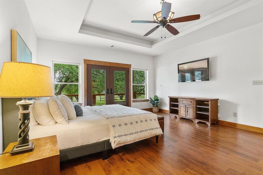 Primary bedroom in home number offers custom flooring, coffered ceiling and French doors leading to the private patio