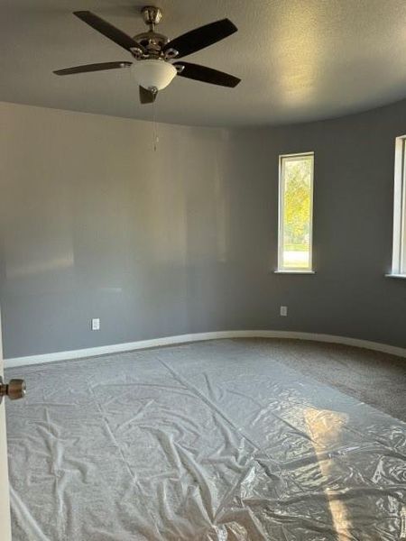 Carpeted spare room with a textured ceiling and ceiling fan
