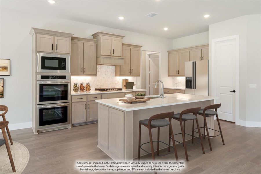 Kitchen with tan cabinets, large island with seating, stainless steel appliances, and tile backsplash