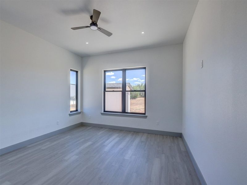 High ceilings and clean plank flooring define this airy secondary bedroom.