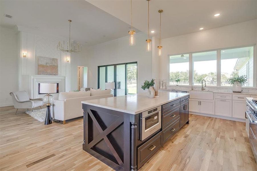 Kitchen with white cabinets, decorative light fixtures, and a healthy amount of sunlight