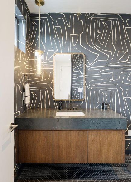 Powder room featuring a custom floating vanity with a dark stone countertop, an integrated rectangular sink, and a brass-framed mirror