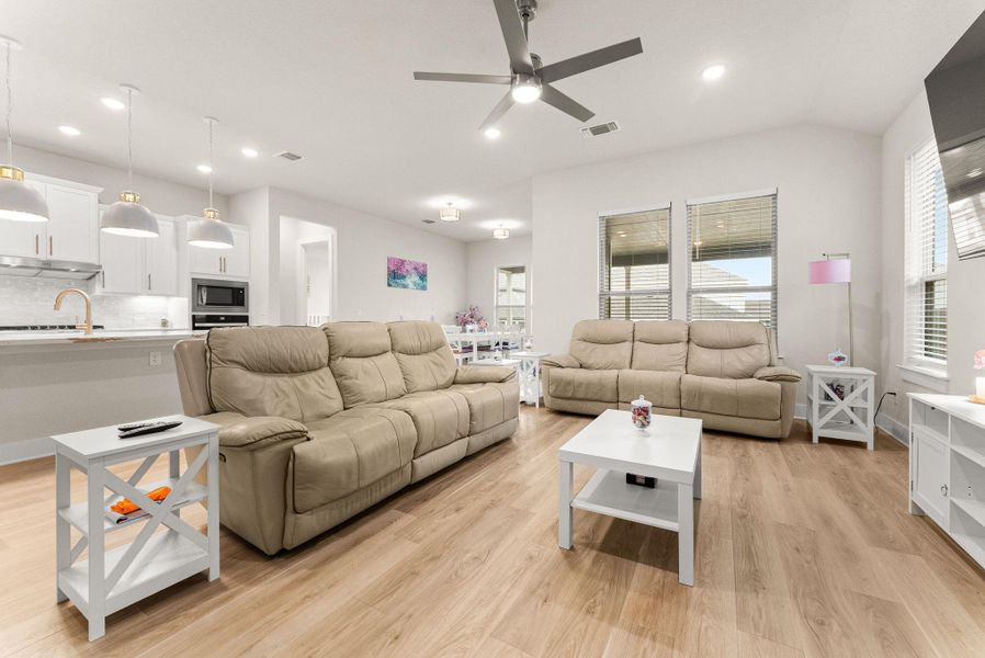 The spacious family room features a corner gas fireplace with mantle, ceiling fan with light, recessed lighting, and two-inch blinds.