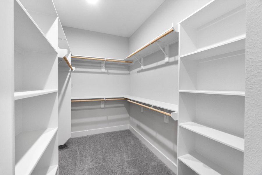 Generously sized walk-in closet with built-in shelving and hanging space, thoughtfully designed for optimal organization.