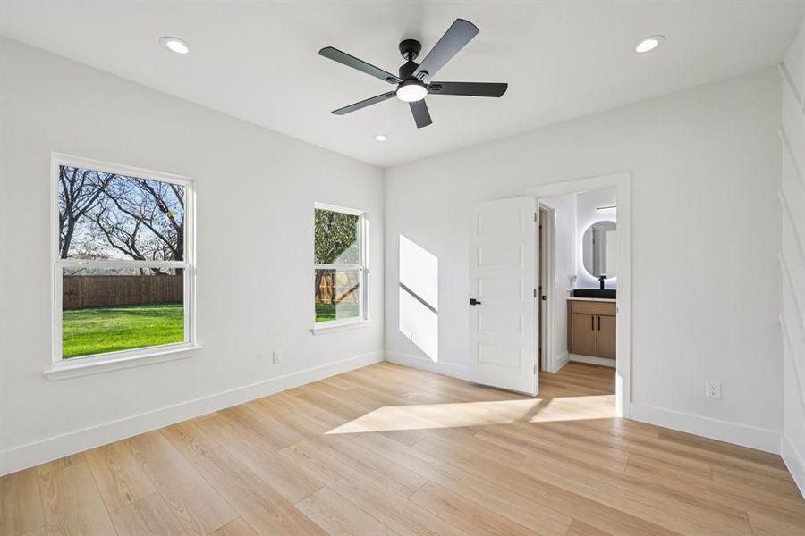 Unfurnished bedroom featuring light wood finished floors, ceiling fan, ensuite bath, and recessed lighting