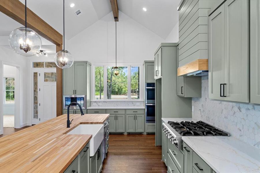 Kitchen featuring decorative backsplash, butcher block counter top, quartz counter top, decorative light fixtures, appliances with stainless steel finishes, beamed ceiling, and dark wood-style flooring Kitchen featuring decorative backsplash, butcher block counter top, quartz counter top, decorative light fixtures, appliances with stainless steel finishes, beamed ceiling, and dark wood-style flooring