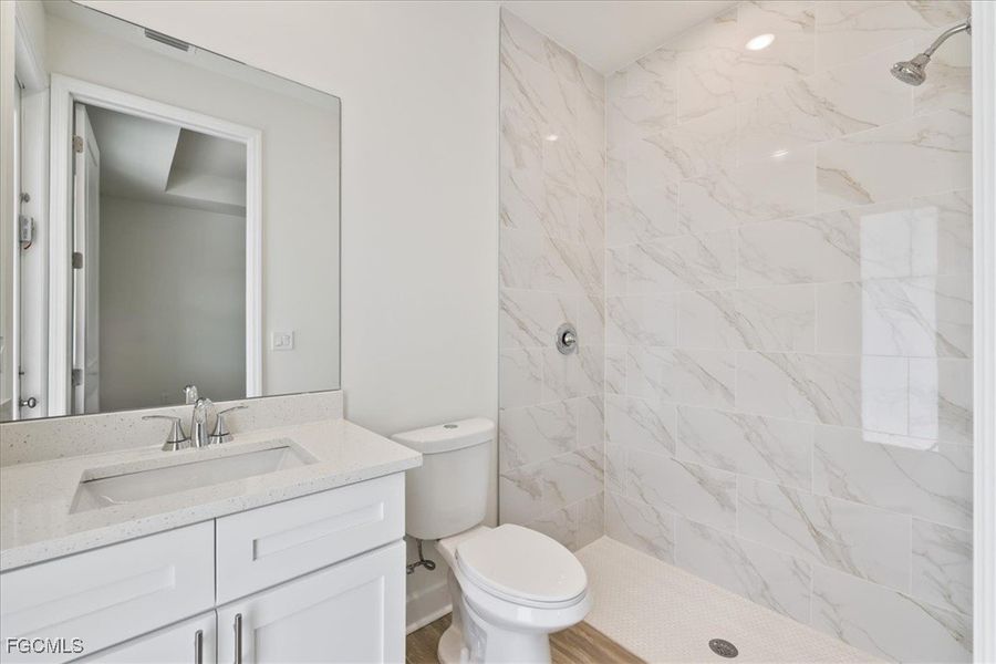 Bathroom featuring a marble finish shower and vanity