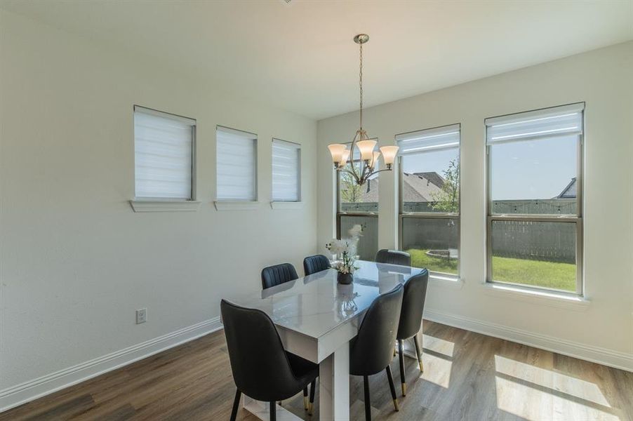 Dining area featuring wood-finish flooring, a tiered chandelier, and multiple windows
