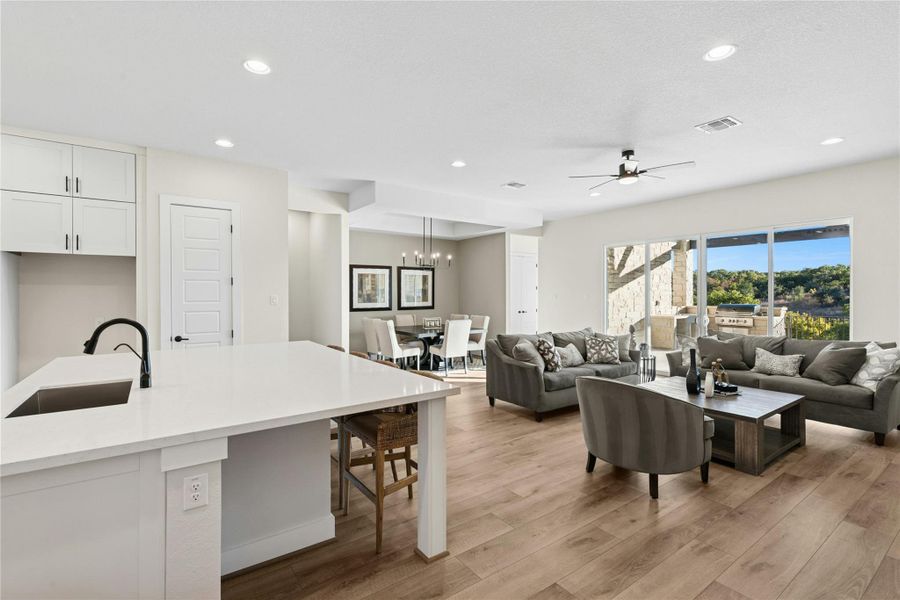 Living area with light wood-type flooring, recessed lighting, a ceiling fan, and a chandelier Living area with light wood-type flooring, recessed lighting, a ceiling fan, and a chandelier