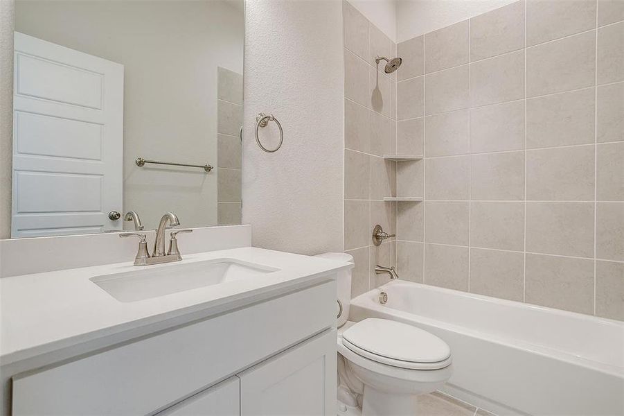 Full bathroom with tiled shower / bath combo, toilet, and vanity