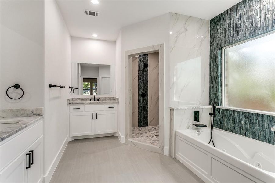 Bathroom featuring vanity, a bath, a marble finish shower, and recessed lighting