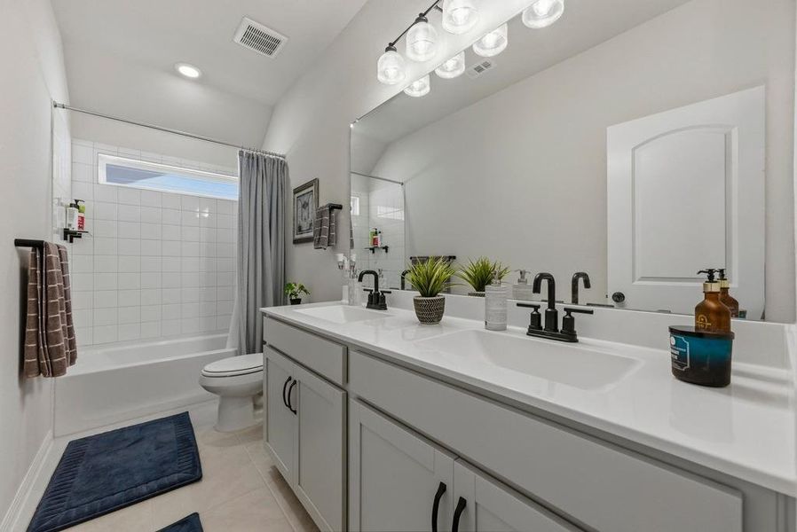Bathroom featuring shower / bath combo, double vanity, and light tile patterned flooring