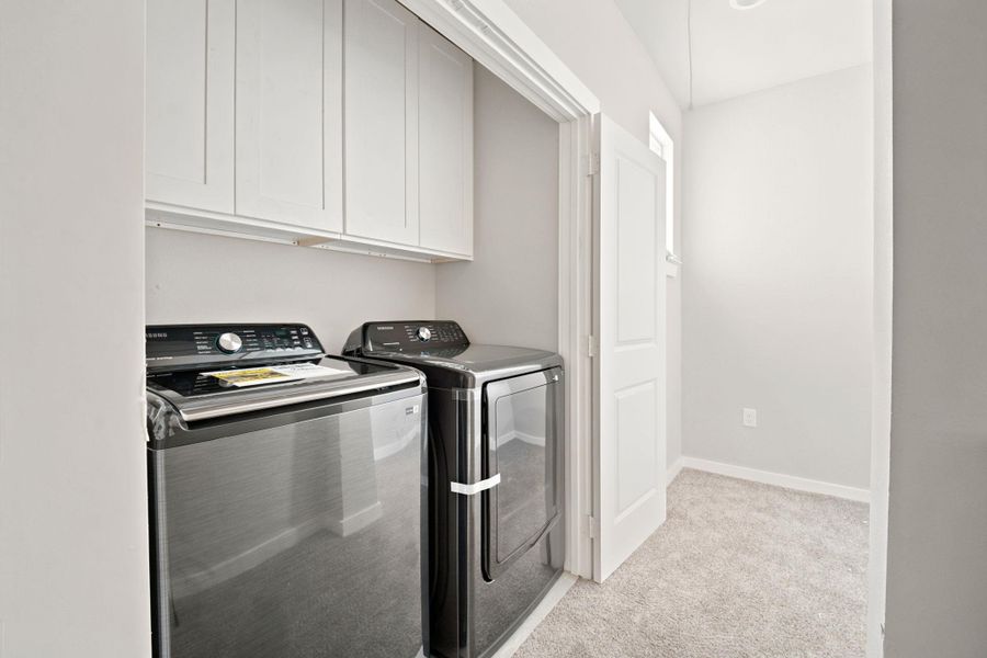 Ample cabinetry and soft carpeting define this functional home utility space.