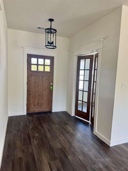 Foyer featuring healthy amount of natural light, dark wood-type flooring, and a chandelier Foyer featuring healthy amount of natural light, dark wood-type flooring, and a chandelier