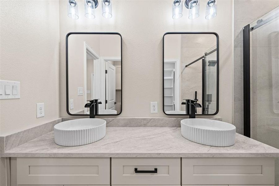 Dual vessel sinks set on a light-toned countertop, featuring matte black faucets