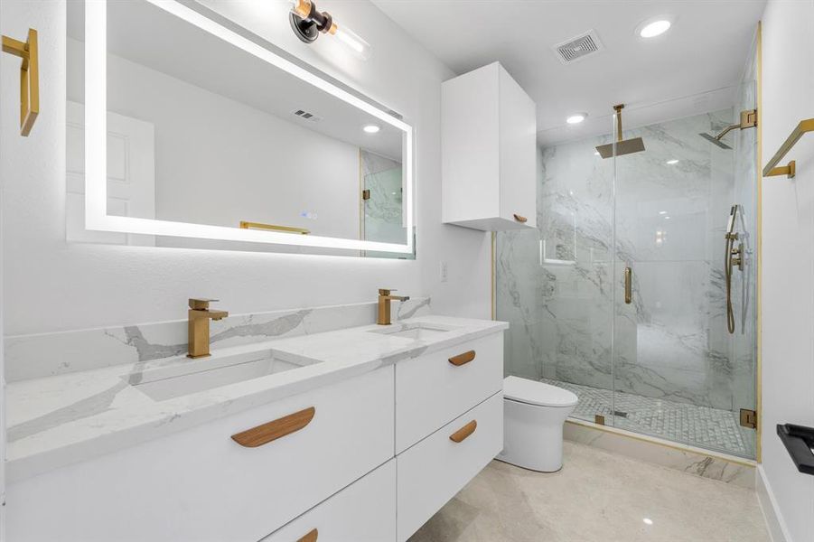 Bathroom with a marble finish shower, toilet, a sink, and visible vents