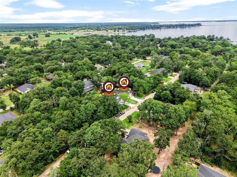 Aerial perspective showcasing residential properties nestled among extensive tree cover, with a body of water in the background Aerial perspective showcasing residential properties nestled among extensive tree cover, with a body of water in the background