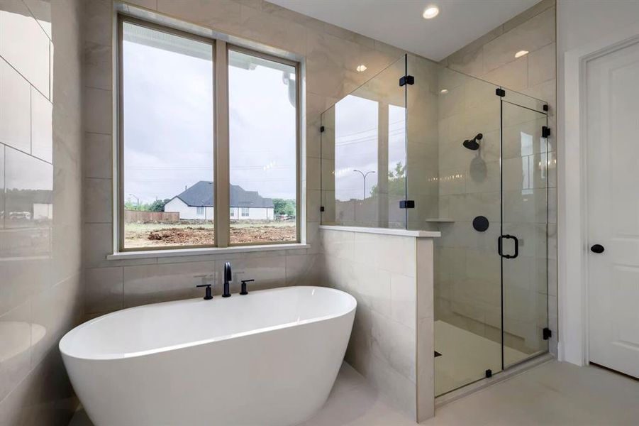 Contemporary bathroom featuring a freestanding tub, a large window, a glass-enclosed shower, and tiled walls and floors