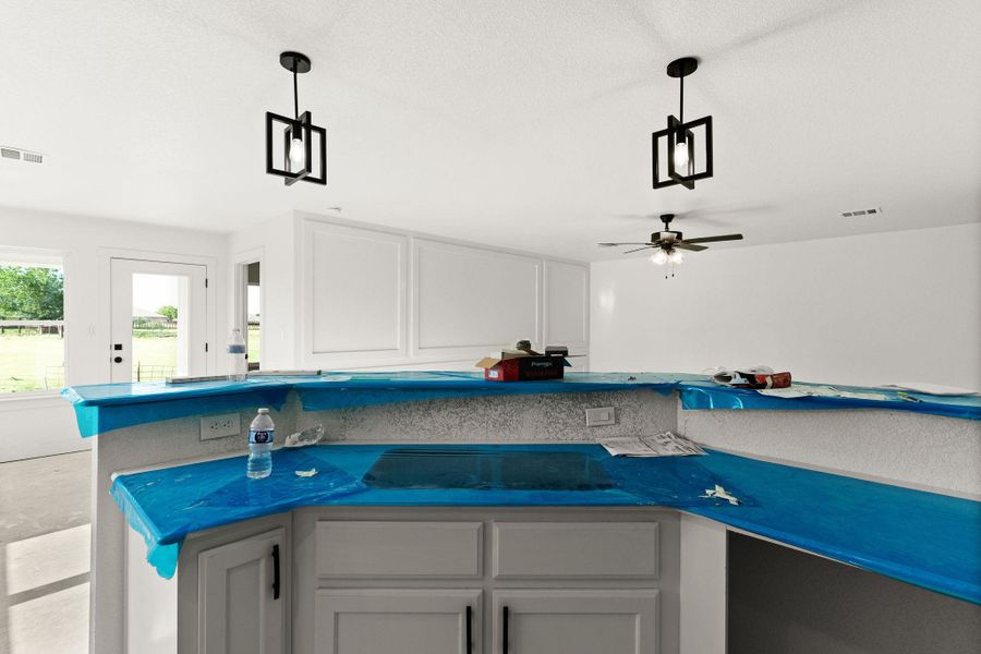 Kitchen featuring pendant lighting, a ceiling fan, white cabinets, and dark countertops Kitchen featuring pendant lighting, a ceiling fan, white cabinets, and dark countertops