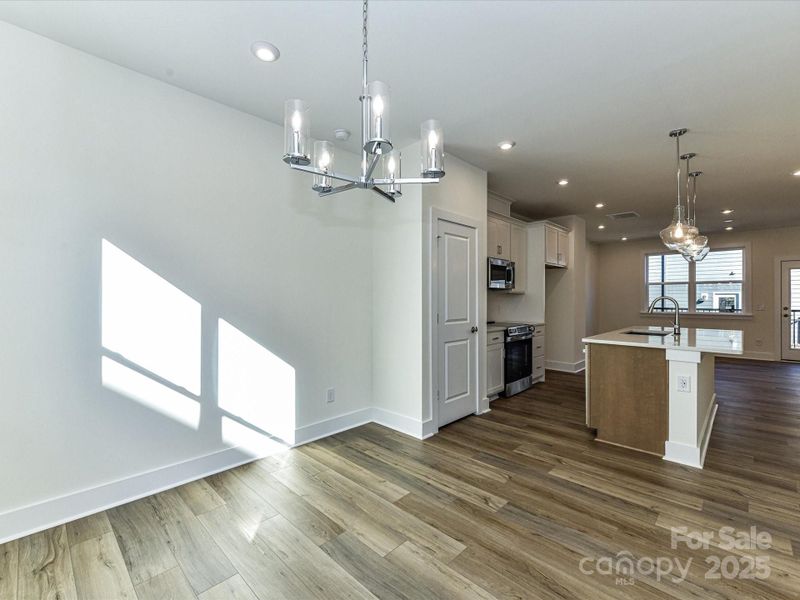 Dining Space Conveniently off Kitchen with Designer Light Fixture.