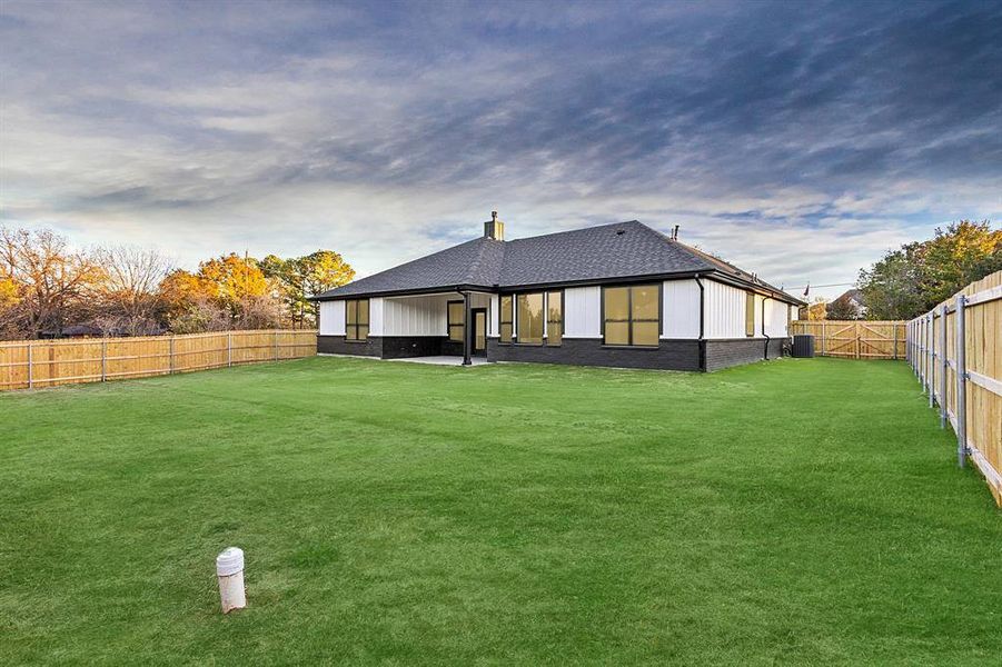 Back of property with a patio area, a fenced backyard, roof with shingles, brick siding, and a chimney