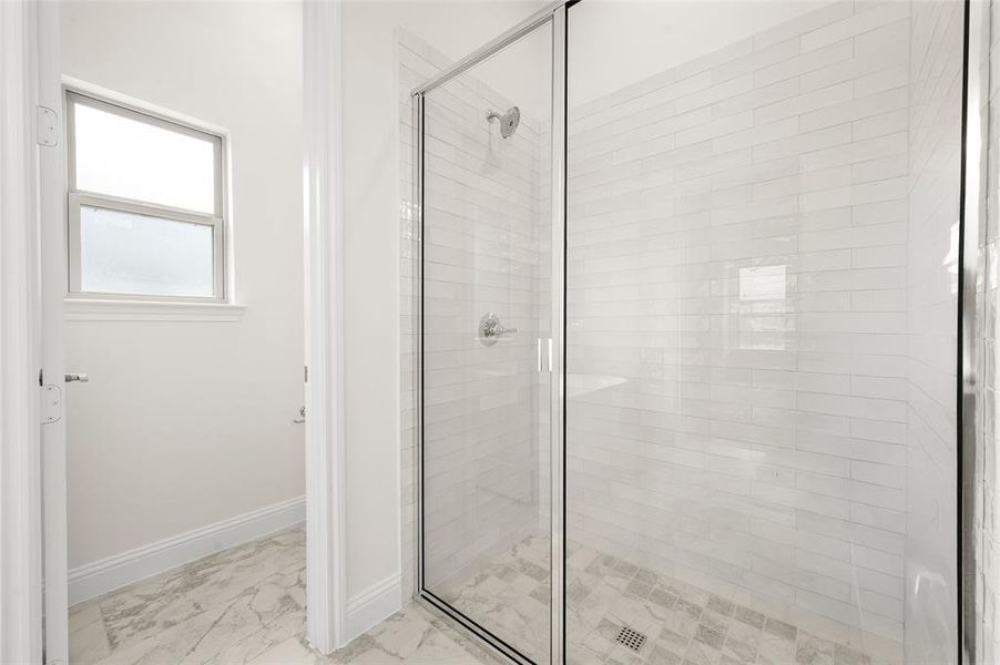Bathroom featuring marble finish flooring and a shower stall