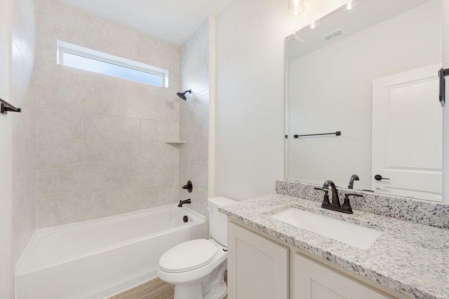 Bathroom with tiled tub-shower combo, granite countertop vanity, and dark bronze fixtures