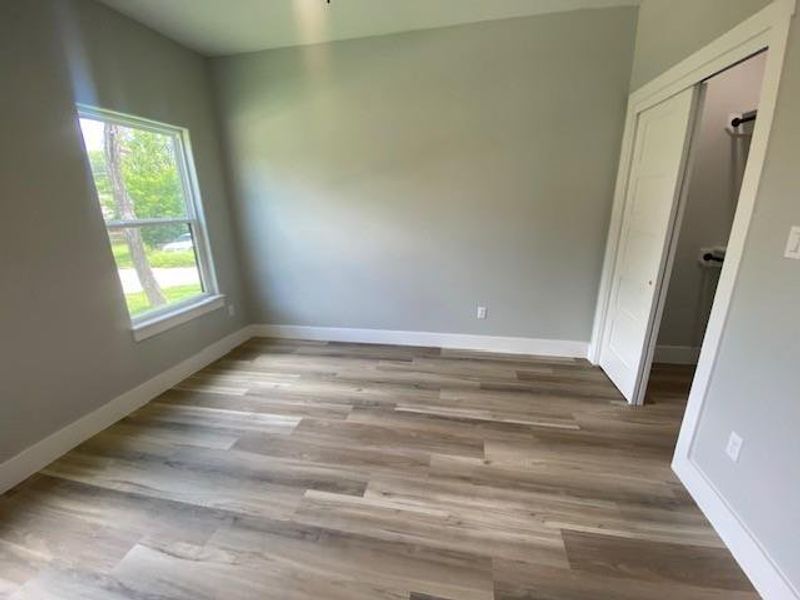 Well-lit living area featuring rich hardwood flooring and convenient closet access. Well-lit living area featuring rich hardwood flooring and convenient closet access.
