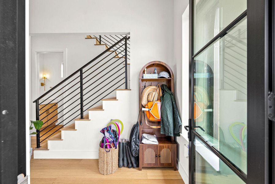 Gleaming hardwood floors and a modern staircase with metal railings welcome guests inside.