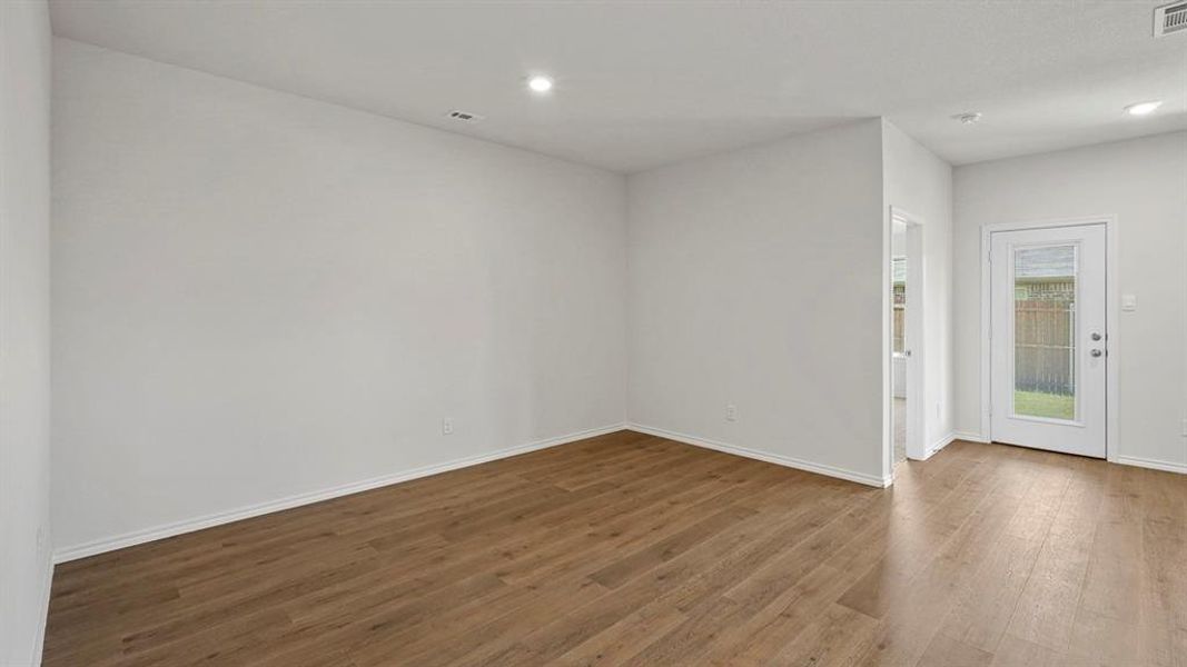 Bright interior space with wood-finish flooring, white walls, recessed lighting, and a glass-paneled exterior door