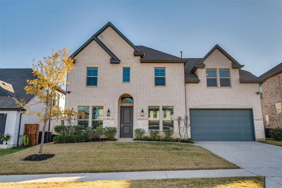 View of front facade with a front lawn, driveway, brick siding, and an attached garage View of front facade with a front lawn, driveway, brick siding, and an attached garage