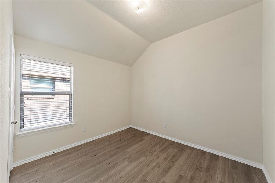 Empty room with lofted ceiling and hardwood / wood-style floors