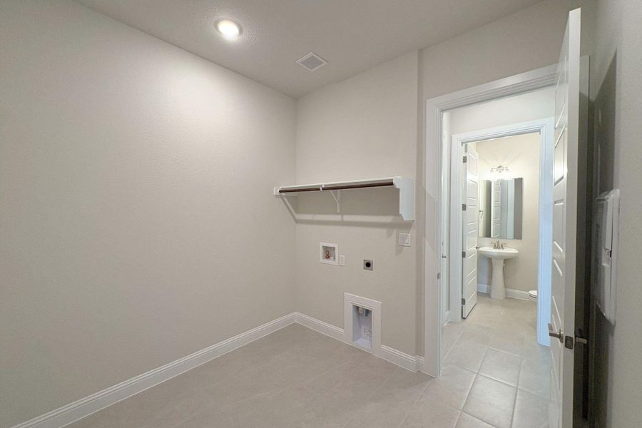 Utility room featuring a built-in shelf with hanging rod, tile flooring, and a recessed ceiling light