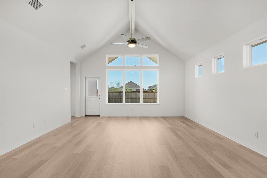 Spare room featuring light wood-type flooring, beamed ceiling, a ceiling fan, and high vaulted ceiling