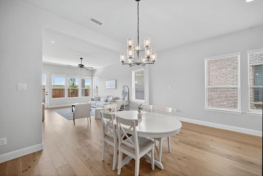 Open-concept living space with light-toned wood-finish flooring, a contemporary chandelier, and recessed lighting