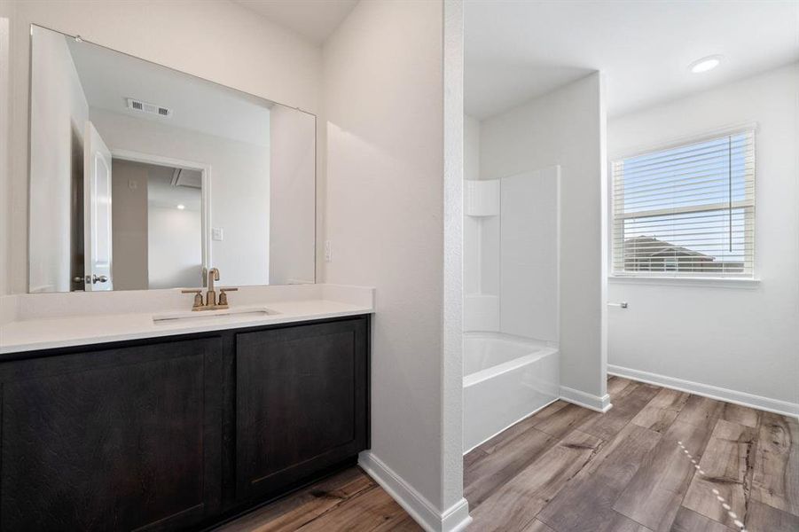 Bathroom featuring  shower combination, hardwood / wood-style flooring, and vanity