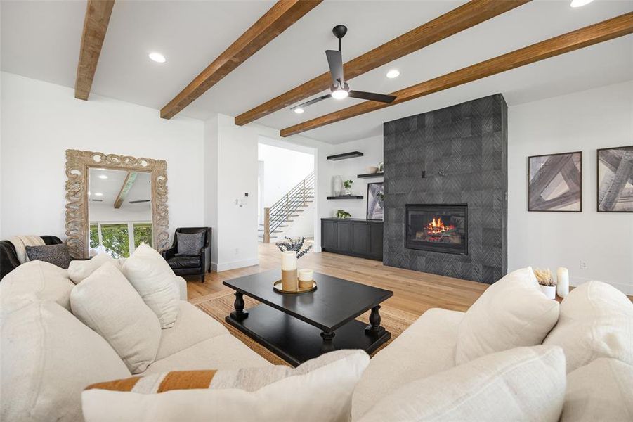Living room featuring recessed lighting, beamed ceiling, a tile fireplace, light wood-style flooring, and stairs Living room featuring recessed lighting, beamed ceiling, a tile fireplace, light wood-style flooring, and stairs