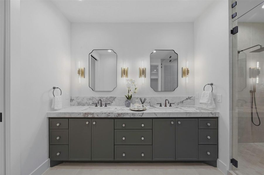Luxurious primary bathroom showcases custom white oak vanities with a seamless cut quartzite countertop slab detailing and highlighting the designer finishes.