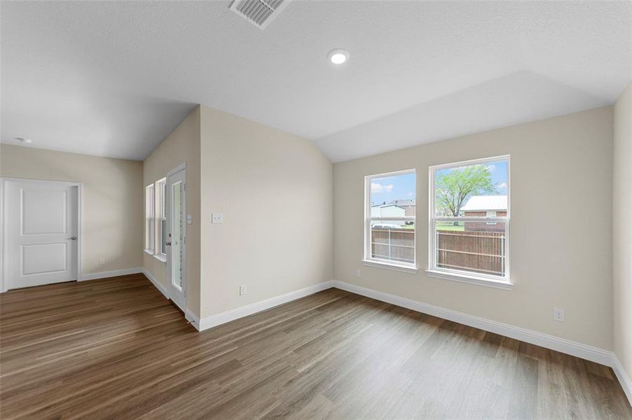 Spacious room featuring wood-finish flooring, light neutral wall tones, and recessed ceiling lighting