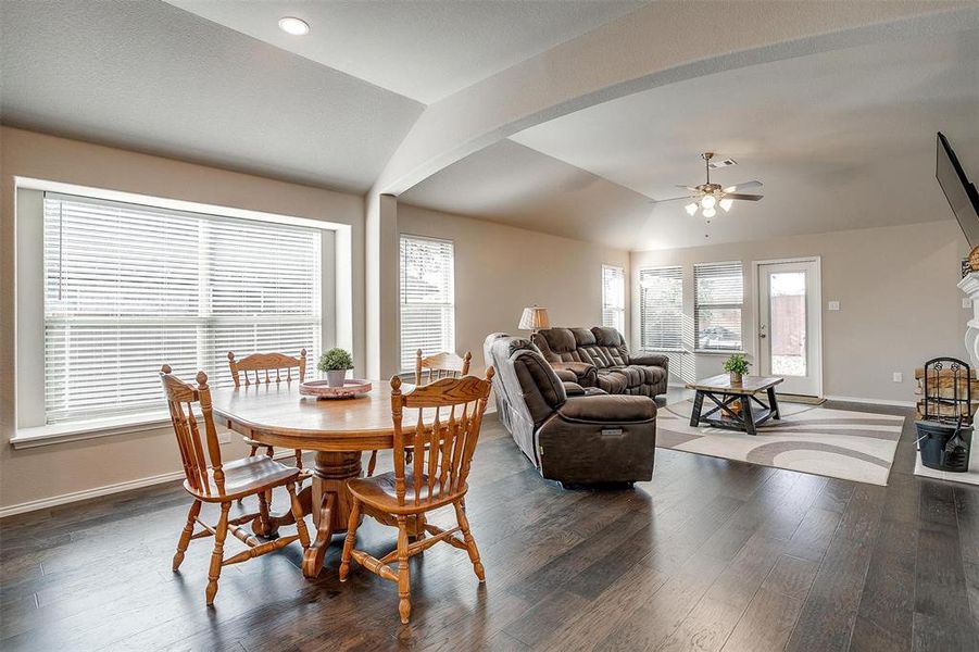 Dining room with ceiling fan, dark wood-type flooring, and vaulted ceiling