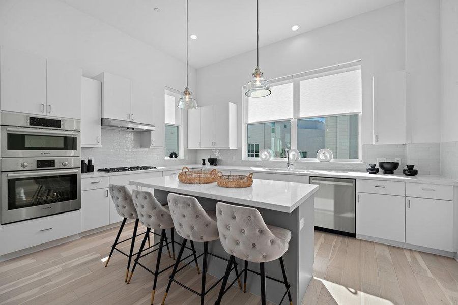 Kitchen featuring white cabinets, decorative backsplash, a kitchen bar, pendant lighting, and recessed lighting