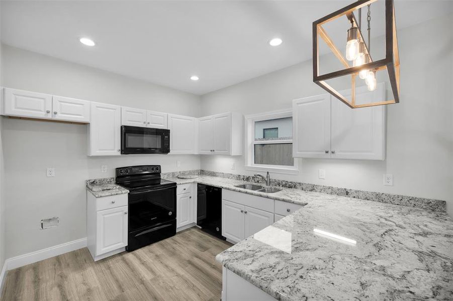 Kitchen featuring light stone countertops, light wood finished floors, a sink, and black appliances Kitchen featuring light stone countertops, light wood finished floors, a sink, and black appliances
