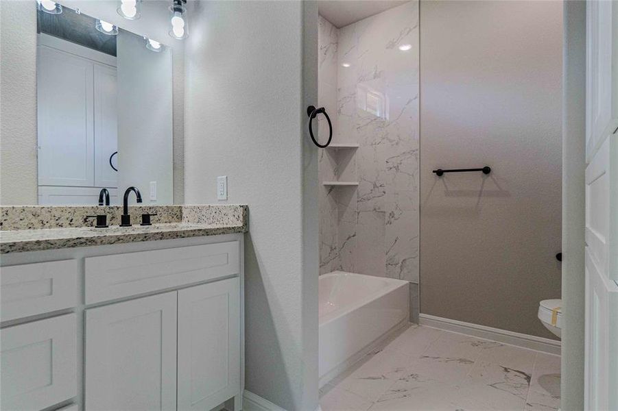 Full bathroom featuring vanity, tiled shower / bath combo, toilet, and tile patterned flooring