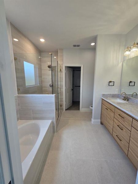 Bathroom featuring a bath, vanity, a stall shower, light tile patterned floors, and recessed lighting